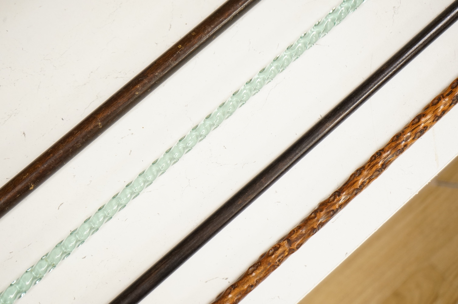 Four walking sticks to include a Brigg of London with carved horn handle in the form of a dogs head and a barley twist glass example, largest 123cm in length